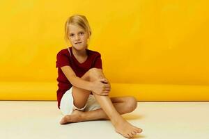 pequeno menina sentado em a chão posando dentro casual roupas foto