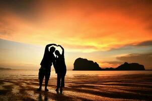 romântico casal segurando mãos às pôr do sol em de praia foto