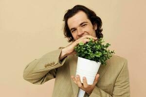alegre homem com uma flor Panela dentro dele mãos clássico estilo bege fundo foto