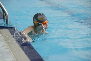 uma Garoto dentro uma natação boné e óculos é natação dentro a Esportes piscina. foto