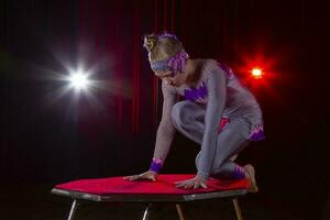 menina circo acrobata ginasta em etapa em uma Sombrio fundo. foto