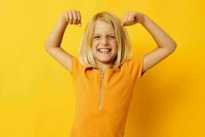 pequeno menina dentro uma amarelo camiseta sorrir posando estúdio infância estilo de vida inalterado foto