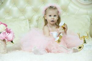 criança de dois anos criança. lindo pequeno menina dentro a elegante Rosa vestir com uma retro telefone. foto