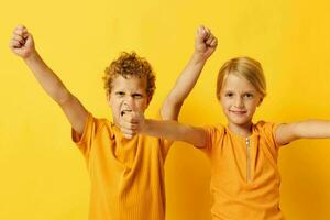 retrato do fofa crianças dentro amarelo Camisetas em pé lado de lado infância emoções amarelo fundo inalterado foto