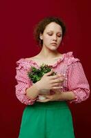lindo mulher dentro Rosa blusa é posando com uma plantar dentro branco Panela foto