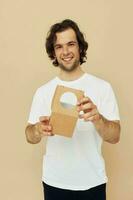 alegre homem dentro uma branco camiseta com uma cartão caixa dentro dele mãos foto