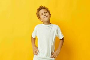 fofa Garoto com encaracolado cabelo dentro uma branco camiseta em uma amarelo fundo foto