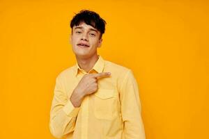 alegre homem dentro amarelo camisa posando moda gesto com mãos foto