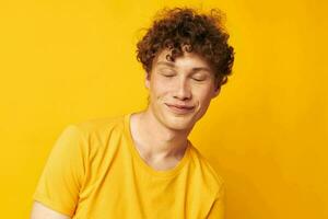 retrato do uma jovem encaracolado homem amarelo camiseta moda mão gestos isolado fundo inalterado foto