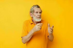retrato do feliz Senior homem mão gesto cinzento barba Diversão amarelo fundo foto