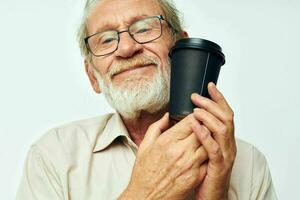 retrato do feliz Senior homem com uma cinzento barba dentro uma camisa e óculos luz fundo foto