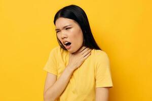 encantador jovem ásia mulher dentro uma amarelo camiseta segurando dele cabeça descontentamento estúdio modelo inalterado foto