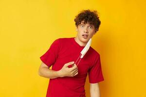 cara com vermelho encaracolado cabelo dentro uma vermelho camiseta médico mascarar proteção estilo de vida inalterado foto