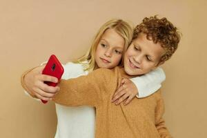 pequeno Garoto e menina com uma vermelho telefone juntos tecnologias isolado fundo foto