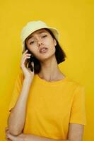 lindo menina dentro uma amarelo chapéu juventude estilo casual falando em a telefone isolado fundo foto