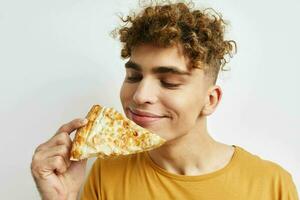 bonito cara comendo pizza posando fechar-se luz fundo foto