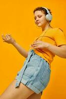 engraçado menina ouvindo para música em fones de ouvido juventude estilo amarelo fundo inalterado foto