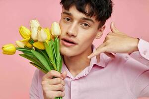 bonito cara dentro uma Rosa camisa com uma ramalhete do flores gesticulando com dele mãos isolado fundo inalterado foto