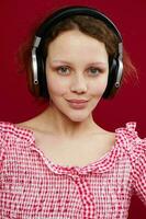 sorridente menina dentro Rosa camisa vestindo fones de ouvido ouvindo para música fechar-se foto