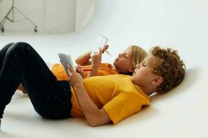 dois alegre crianças desenhando dentro cadernos deitado em a chão luz fundo inalterado foto