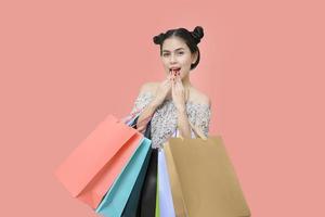 mulher compradora atraente segurando sacolas de compras no fundo salmão foto