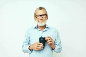 retrato do feliz Senior homem com uma Preto vidro dentro dele mãos uma beber isolado fundo foto