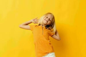 lindo pequeno menina dentro uma amarelo camiseta sorrir posando estúdio infância estilo de vida inalterado foto