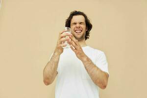 alegre homem dentro uma branco camiseta com uma caneca dentro mão bege fundo foto