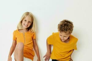 dois alegre crianças dentro amarelo Camisetas em pé lado de lado infância emoções luz fundo inalterado foto