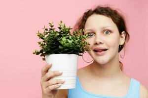 retrato do uma jovem mulher dentro uma azul camiseta e calção uma vaso de flores isolado fundos inalterado foto