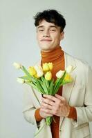 uma jovem homem dentro branco Jaqueta com uma ramalhete do amarelo flores elegante estilo Rosa fundo inalterado foto