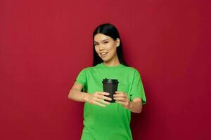 mulher com ásia aparência dentro uma verde camiseta uma vidro do beber Diversão isolado fundo inalterado foto