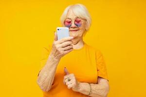 sorridente idosos mulher dentro elegante óculos com uma Smartphone fechar-se emoções foto