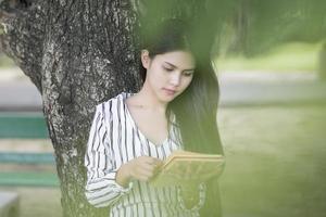 mulher atraente lendo um livro no parque foto