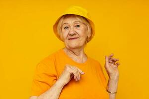 idosos mulher feliz estilo de vida dentro uma amarelo cocar amarelo fundo foto