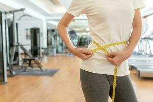 dieta e dieta. beleza fino fêmea corpo usar fita medir. mulher dentro exercício roupas atinge peso perda objetivo para saudável vida, louco sobre magreza, fino cintura, nutricionista. ginástica foto