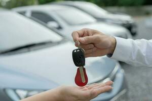 alugar, alugar carro, vender, comprar. o gerente da concessionária envia as chaves do carro para o novo proprietário. vendas, empréstimo de crédito financeiro, aluguel de veículo, seguro, aluguel, vendedor, negociante, prestação, negócio de cuidados com o carro foto