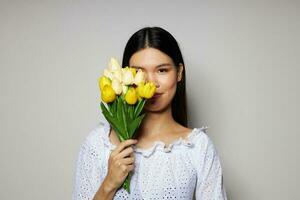 mulher com ásia aparência dentro uma branco camisa flores Primavera posando luz fundo inalterado foto