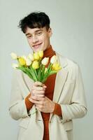 bonita homem dentro branco Jaqueta com uma ramalhete do amarelo flores elegante estilo modelo estúdio foto