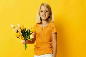 pequeno menina com loiro cabelo com uma ramalhete do amarelo flores em uma amarelo fundo foto