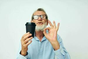 retrato do feliz Senior homem gestos com dele mãos uma vidro do beber isolado fundo foto