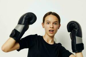 lindo menina dentro boxe luvas dentro Preto calça e uma camiseta ginástica Treinamento foto