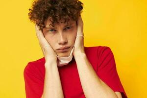 cara com vermelho encaracolado cabelo dentro protetora máscaras segurança posando amarelo fundo inalterado foto