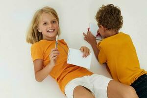 cenário do positivo Garoto e menina desenhando dentro cadernos deitado em a chão luz fundo inalterado foto