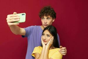 uma jovem casal dentro colorida Camisetas com uma telefone juventude estilo foto