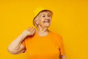 foto do aposentado velho senhora feliz estilo de vida dentro uma amarelo cocar amarelo fundo