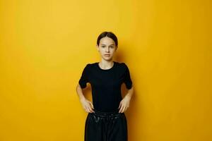 lindo menina dentro uma Preto camiseta e calça sorrir amarelo fundo foto