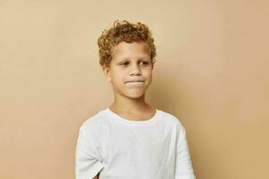 Garoto com encaracolado cabelo dentro uma branco camiseta posando foto