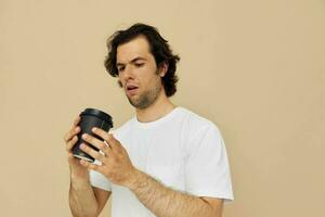 alegre homem dentro uma branco camiseta com uma Preto vidro dentro mão bege fundo foto