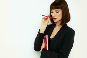 retrato do uma mulher vermelho bloco de anotações e lápis posando isolado fundo foto